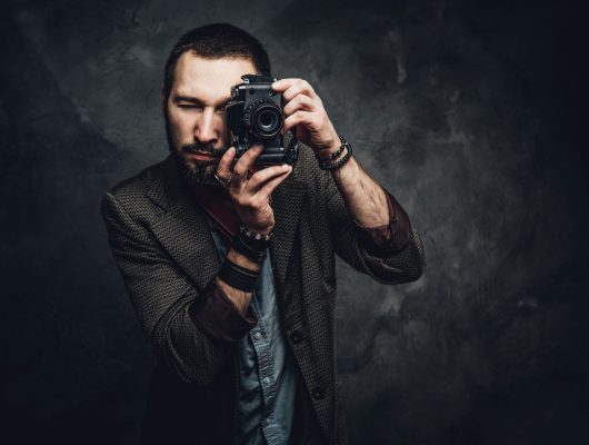 focused-young-photographer-is-taking-photo-dark-grunge-background